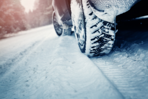 Car tires on winter road covered with snow. Vehicle on snowy way in the morning at snowfall